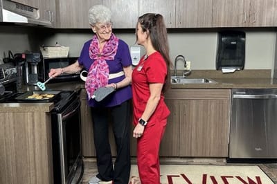 A resident and staff member cooking together in a kitchen