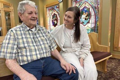 Resident smiling with staff in a facility common area