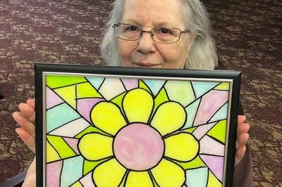 Resident holding a colorful stained glass flower art piece