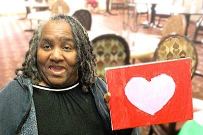 Resident holding painting in an activity room