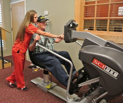 Staff assisting a resident with rehabilitation equipment