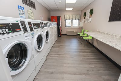 Laundry room with washing machines and seating.