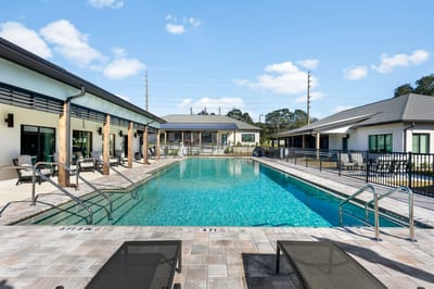 Swimming pool area with lounge chairs and surrounding buildings