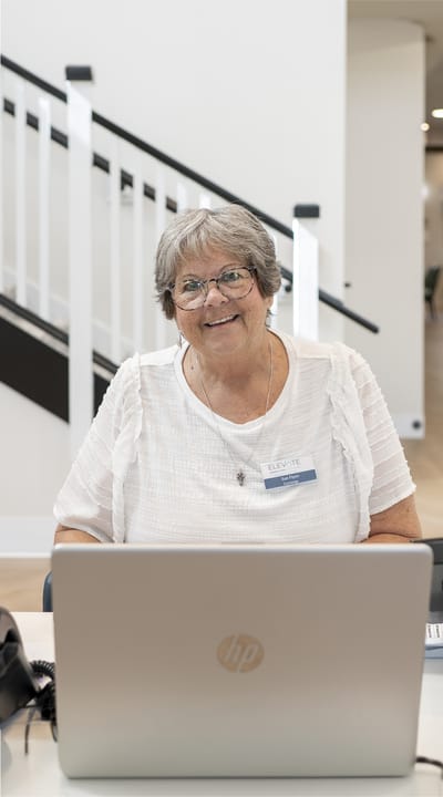 Senior staff member smiling at a desk with a laptop