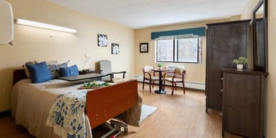 Cozy resident room with bed, chair, and small dining area