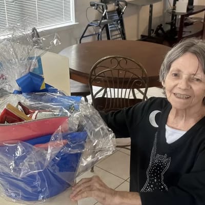 Resident smiling with a gift basket in a common area