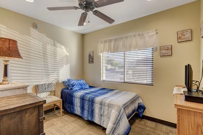 A cozy resident room with a twin bed and window