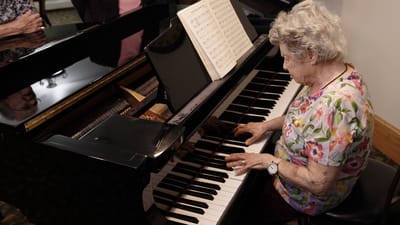 A resident playing piano in a bright common area