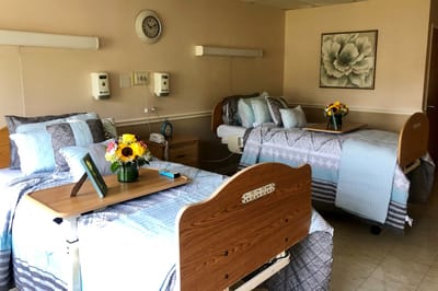 Shared resident room with two beds and floral arrangements