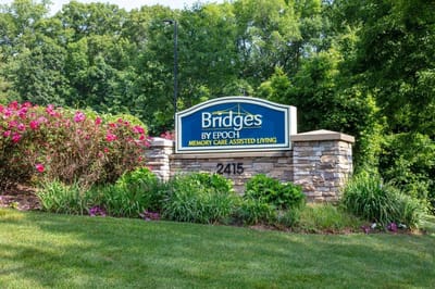 Sign for Bridges by Epoch at Trumbull surrounded by flowers.