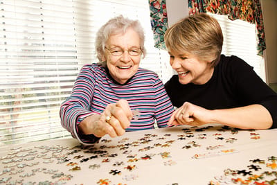 Resident and staff member enjoying a puzzle together.