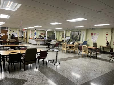 Interior view of a common area with tables and chairs.