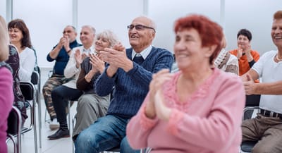 Seniors enjoying a performance, clapping hands.