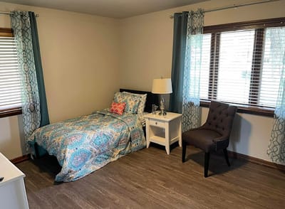 Colorful private resident room with bed and chair.