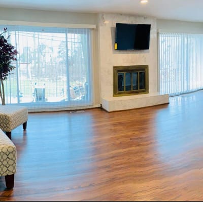 Bright common area with wooden floor and large windows.