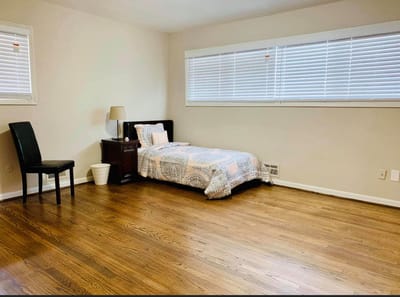 A simple, furnished resident room with a bed and chair.