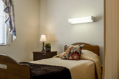 Cozy resident room with a bed and lamp.