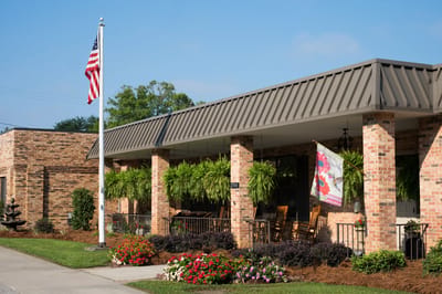Front entrance of the facility with plants and flag