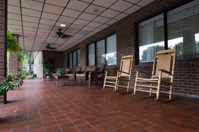 Covered porch with rocking chairs and plants.