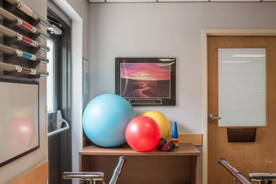 Exercise balls and a colorful poster in a therapy room.