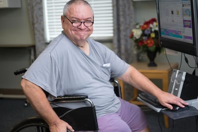 Resident in wheelchair using a computer.
