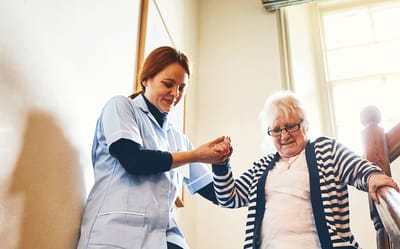 Caregiver assisting an elderly woman on stairs.