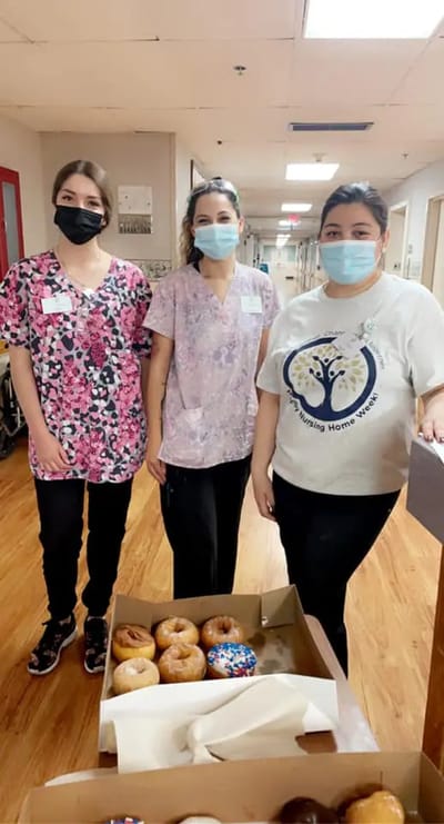 Staff members with a box of donuts in a hallway.