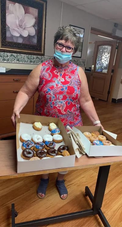Staff member presenting a variety of donuts