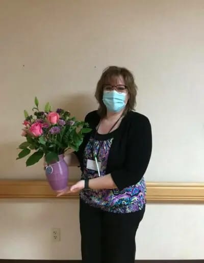 Staff member holding a flower vase indoors.