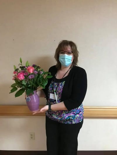 Staff member holding a bouquet of flowers.