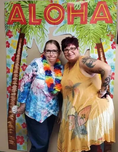 Two residents celebrating with an Aloha theme backdrop.