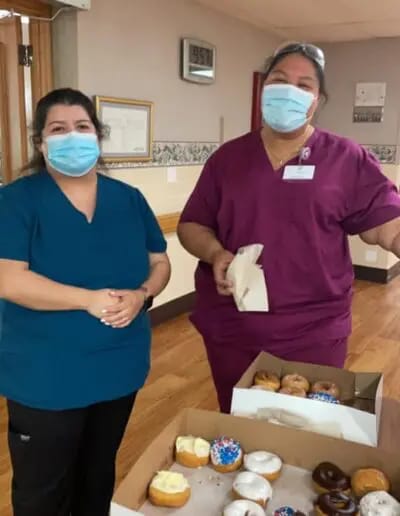 Two staff members with a box of donuts