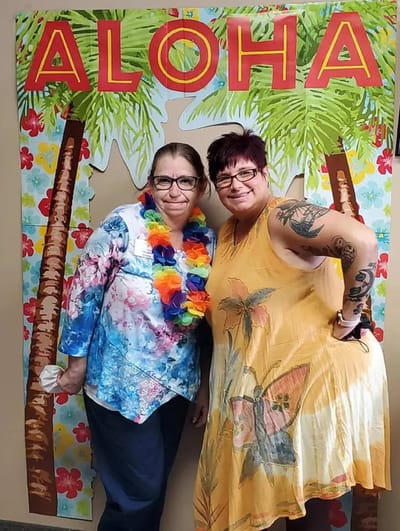 Two smiling residents at a themed event backdrop.
