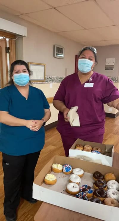 Two staff members with a box of donuts inside the facility