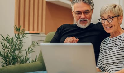 Senior couple engaging with a laptop in a cozy setting.