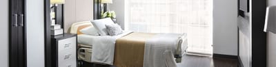 A well-lit private resident room with a bed