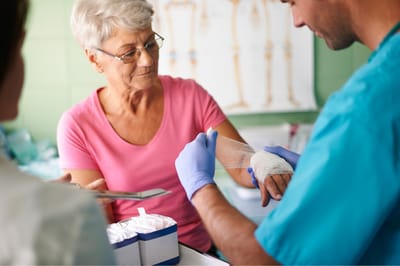 A caregiver dressing a wound for a senior resident