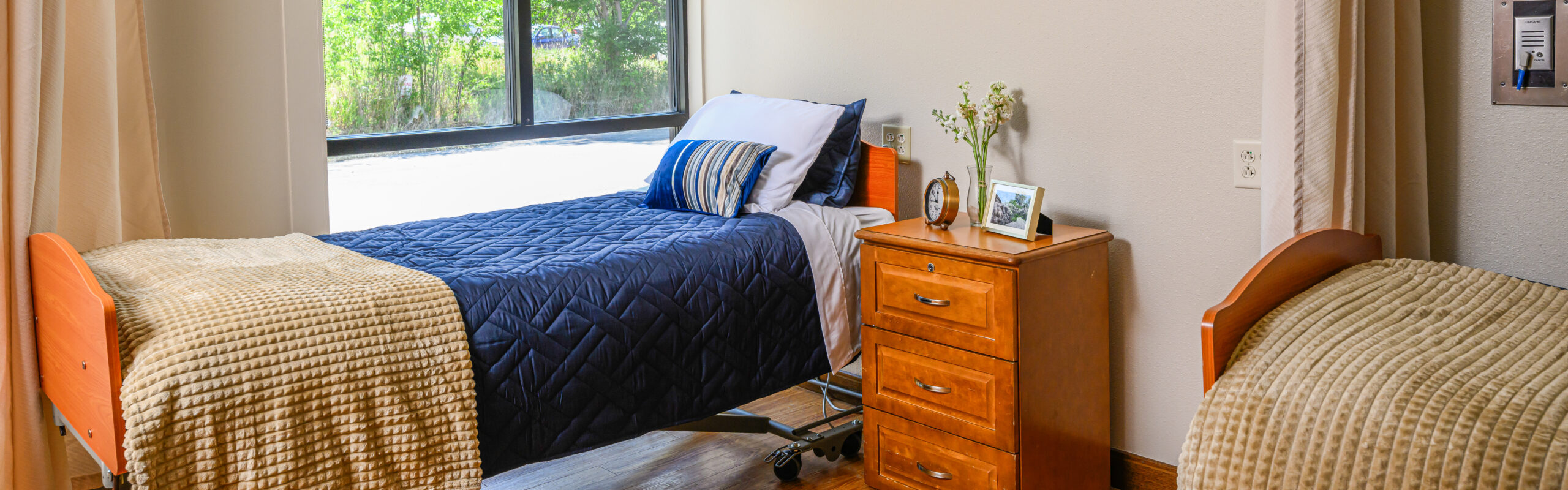 A well-furnished resident room with twin beds and natural light