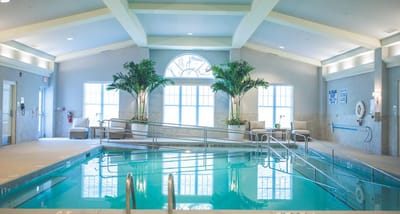 Indoor swimming pool area with palm trees and lounge chairs