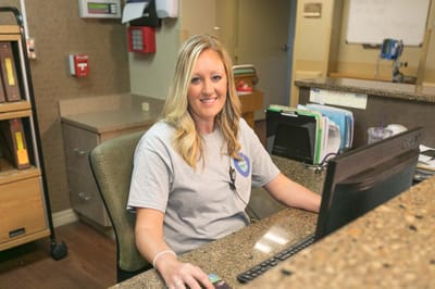 Staff member at the reception desk, assisting residents.