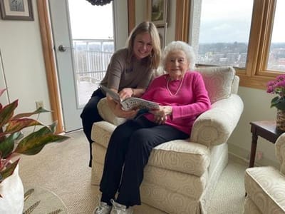 Staff member reading with resident in cozy interior