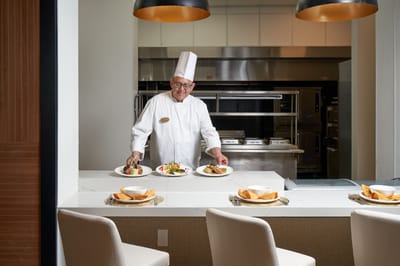Chef presenting plated meals in a dining area.