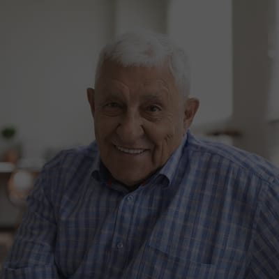 Smiling elderly man in a checkered shirt.