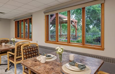 Dining area with tables set and windows overlooking outdoor space
