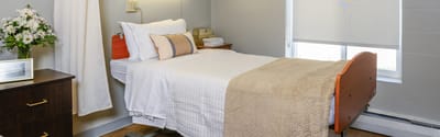 Cozy private resident room with a bed and bedside table