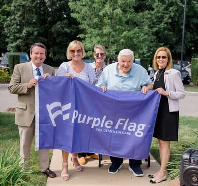 Residents and staff holding a Purple Flag for dementia care