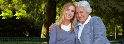 Two women smiling on a bench in a garden