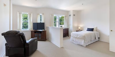 A bright, spacious private resident room with a bed and furniture