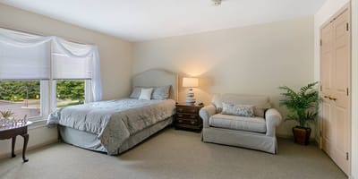 Complete Care At Holmdel Llc, nursing home in Holmdel, NJ — Cozy bedroom with a bed, chair, and lamp