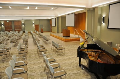 An empty auditorium with chairs and a grand piano